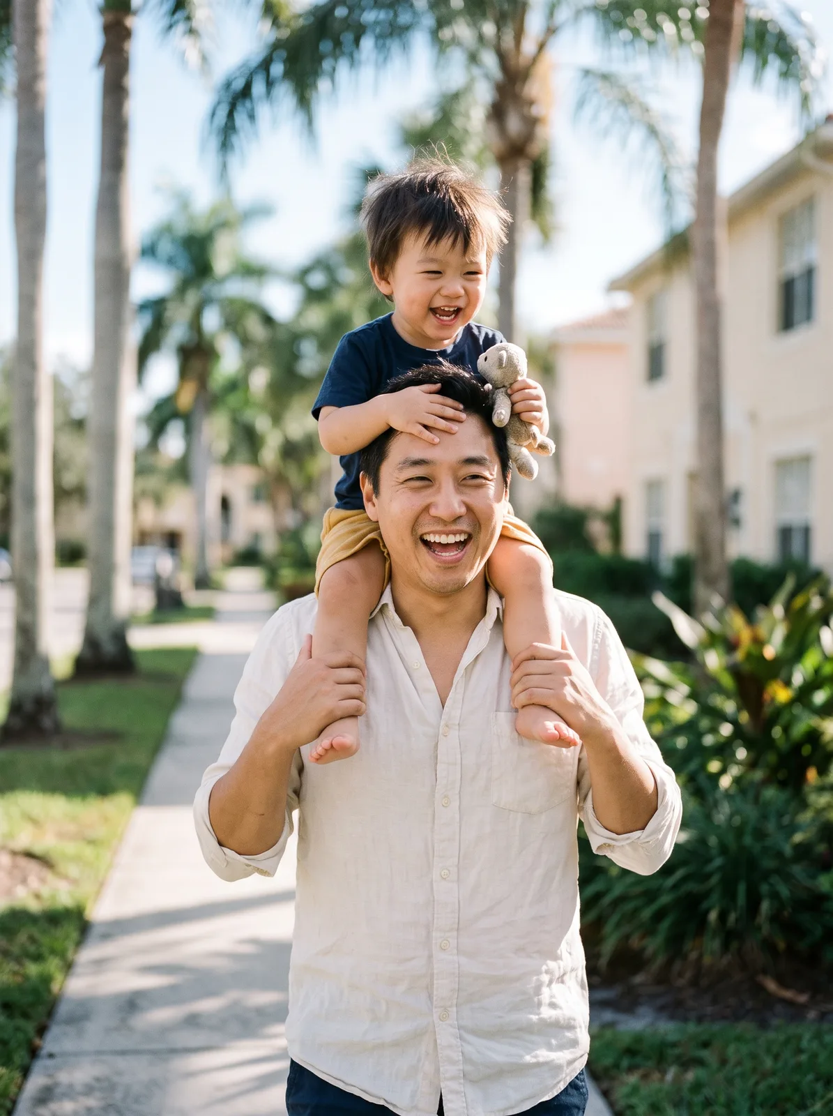 A dad carrying his laughing toddler on his shoulders